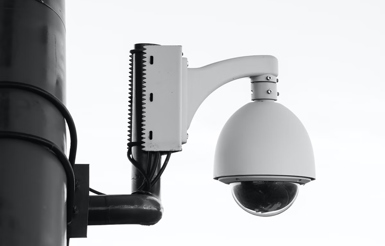 Zoomed in picture of a single security camera on a pole in black and white