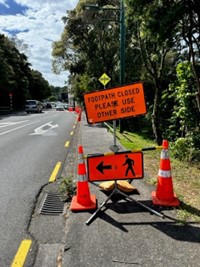 Photo of safety signage used for people so that they are aware the footpath is closed due to a footpath slip in Titirangi Village