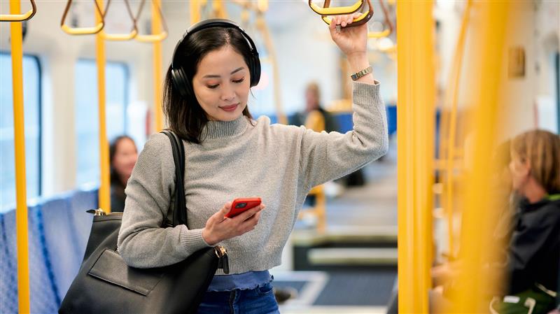 A person standing on a bus and looking at their phone.