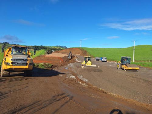Heavy construction equipment works on the new road location.